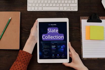 Person holding a tablet displaying HyveIQ Slate Collection on a desk with a keyboard and stationery items.